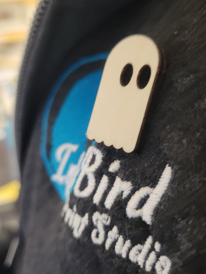 Birch wood ghost-shaped pin with black eyes, laser cut, on a hoodie with blue/white InkBird Print Studio embroidery.