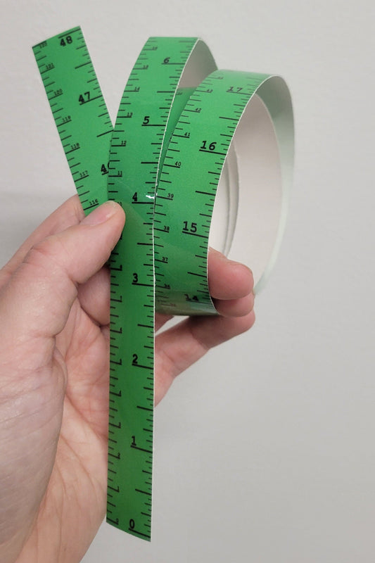 Hand displaying an InkBird Print Studio vertical adhesive vinyl ruler, clear with inch and cm markings on white, ideal for crafts.