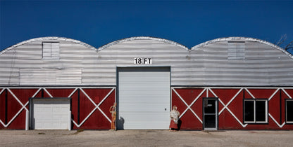 Red and silver metal commercial building with 18 FT white vinyl garage door, standing seam panels, and a bold industrial design.