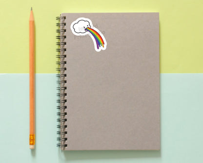 Brown spiral notebook with a glossy vinyl Rainbow Cloud Sticker by InkBird Print Studio, next to a pencil on pastel yellow and blue.